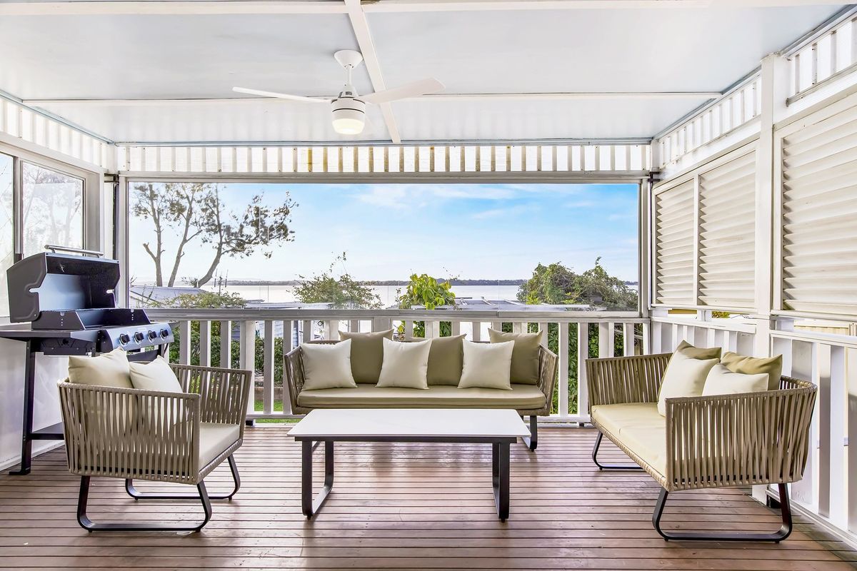 Covered veranda with outdoor living area overlooking the water
